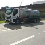 Caminhão tanque branco da Leiroz Ambiental em via asfaltada