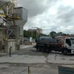 Caminhão tanque em operação ao lado de edifício industrial