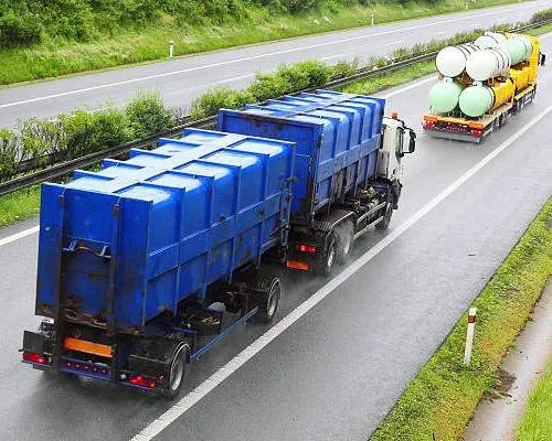 Caminhão com tanques azuis transportando resíduos em rodovia