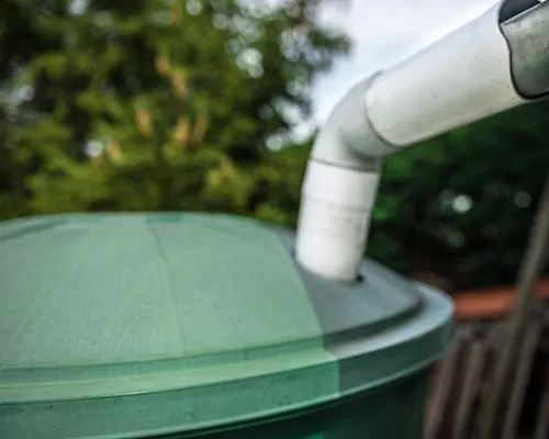 Caixa d’água verde com tubulação branca em jardim