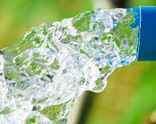 Água jorrando de tubo azul em limpeza de tubulação pluvial