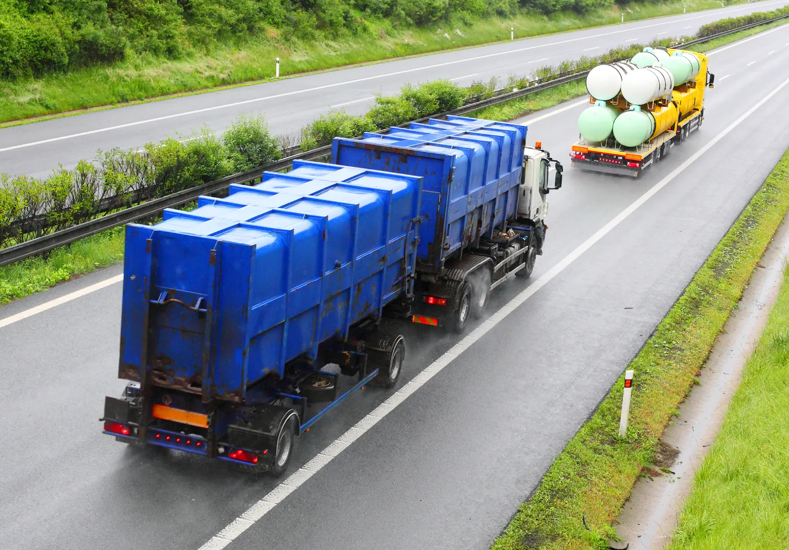 Caminhão com tanques azuis transportando resíduos em rodovia